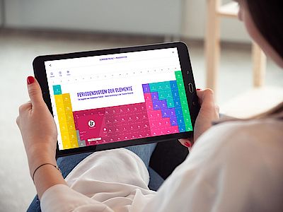 Person schaut auf Online-Version des Periodensystems der Elemente auf einem Tablet